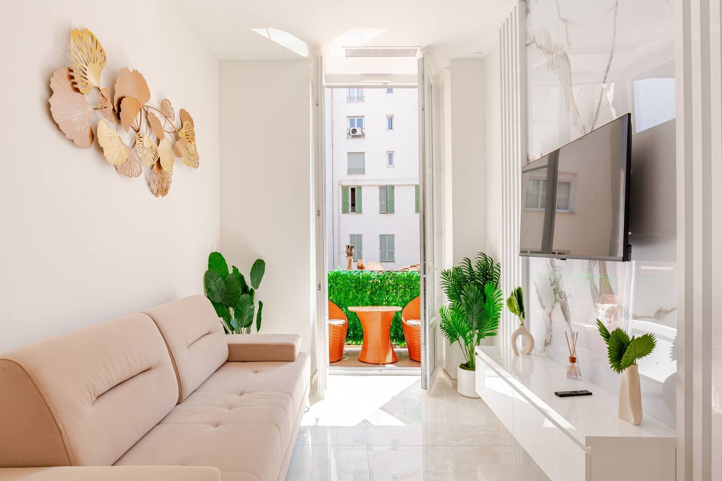Séjour avec canapé rosé, téléviseur mural et plantes vertes
